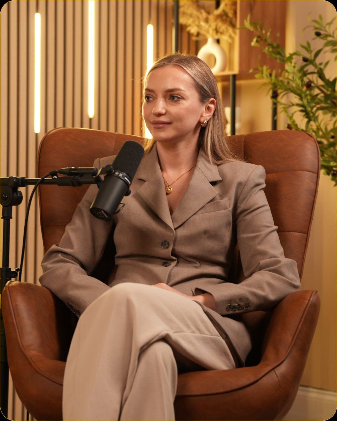 A guest in a beige suit seated at a microphone on a leather armchair in Studio #1