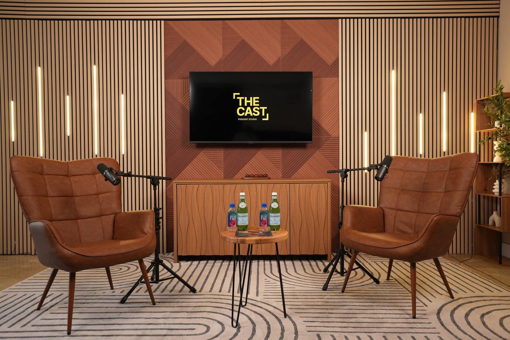 Studio #1 at The Cast Studio: two leather armchairs with microphones in front of an LED light wall and a display showing the studio logo