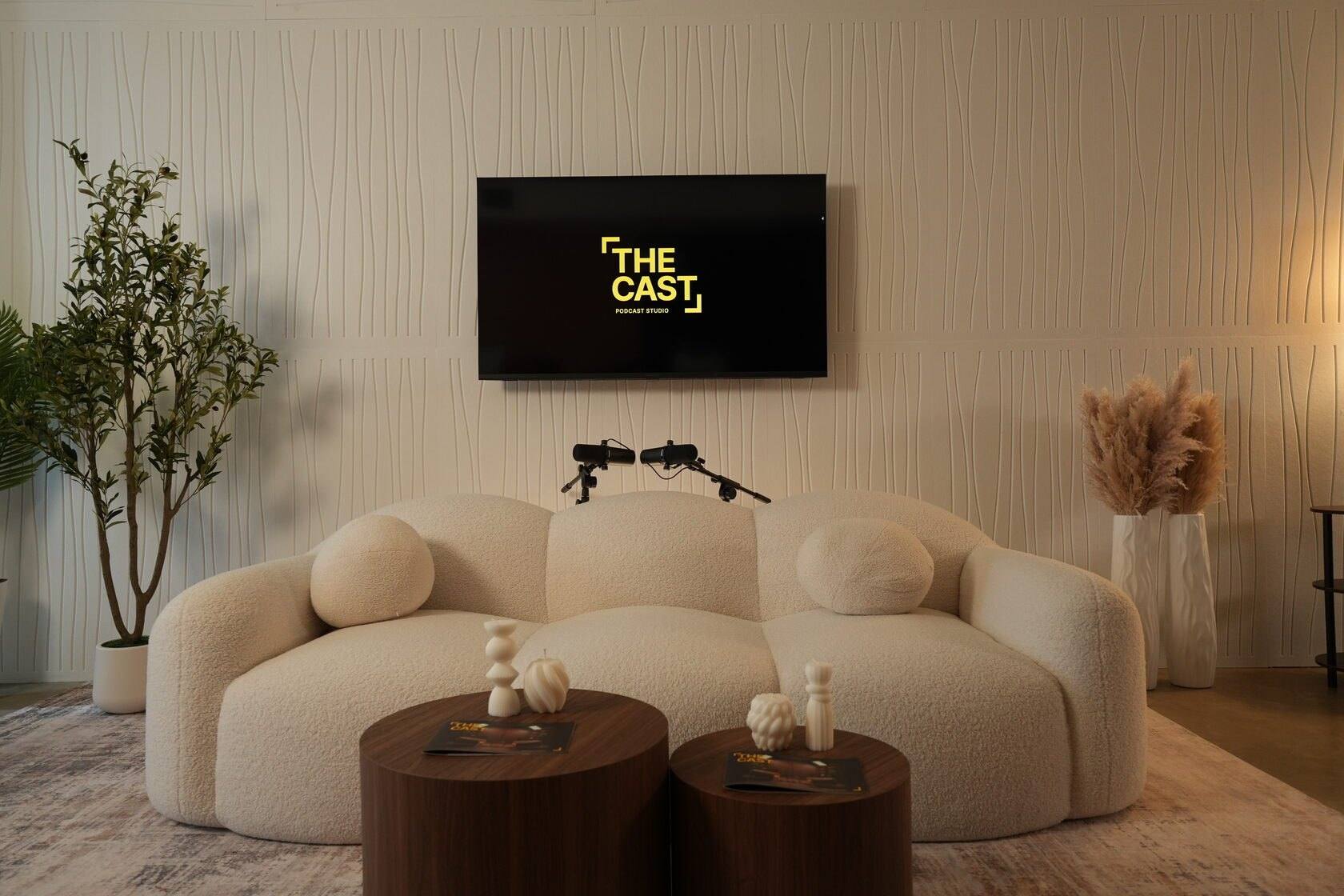 Studio #2 at The Cast Studio: a rounded white sofa, two round wooden tables and a wall display with the studio logo