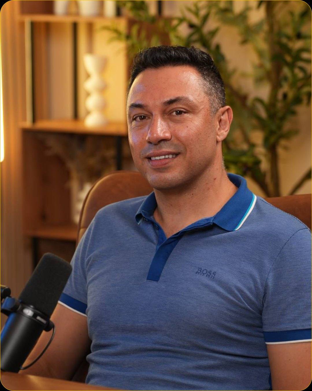 Close-up of a smiling guest in a blue polo at a microphone in Studio #4