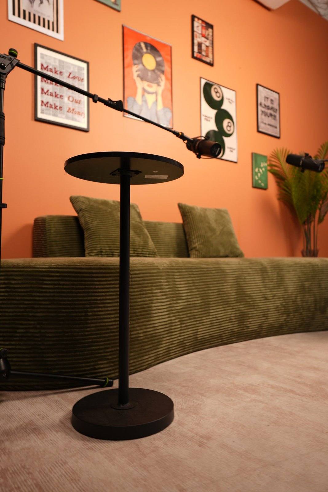 Studio #6 at The Cast Studio: microphones on boom arms and a side table beside a green corduroy sofa