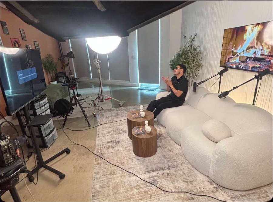 Guest on the white sofa set with cameras and lights around